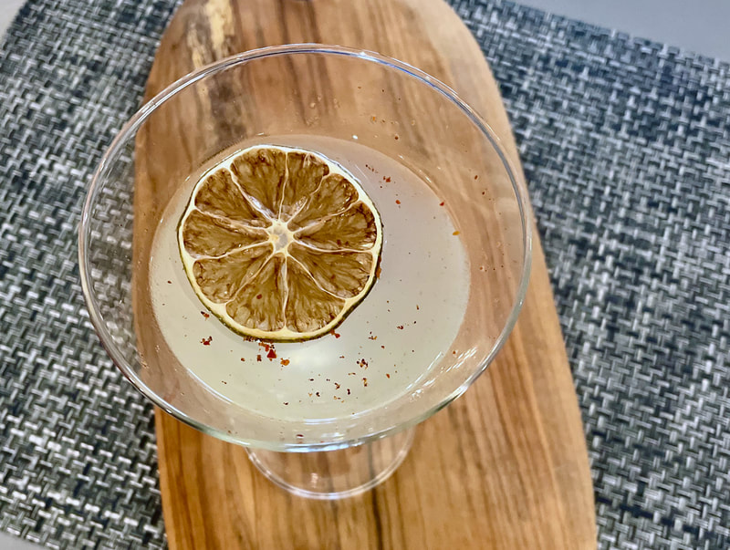 A close up photo taken from overhead of a signature cocktail from Dar, called Aleppo Martini, garnished with a dried lime.