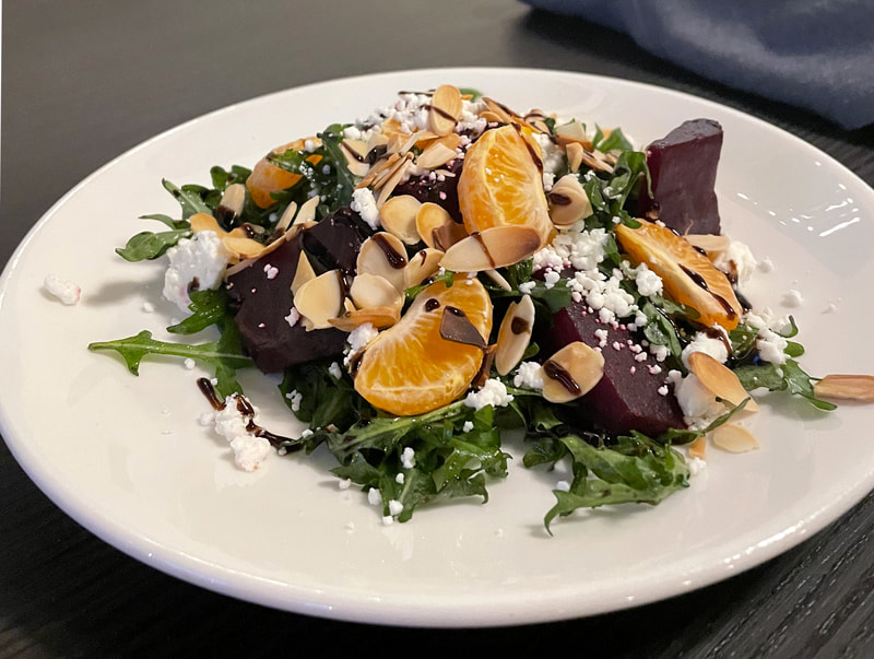 Close-up photograph of a menu item from Dar: TANGY BEET SALAD with spring greens, beets, mandarin oranges, almonds, goat cheese,
olive oil-balsamic dressing
